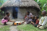 A woman demonstrating hygiene in the kitchen to a woman and her family.