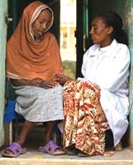 Two women sit chatting to one another.