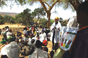 A health professional shows the community brightly coloured posters displaying health information.