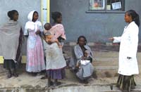A health professional talking to some women from the community whilst sitting outside the health facility.