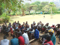 The community gather around to listen to a talk on specific health issues.