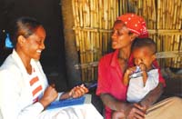 A HEP talks to a mother whilst her child sits on her lap.