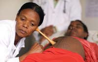A healthcare worker listens to the baby's heartbeat in the womb.