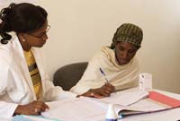 A healthcare worker is seated with a patient looking at her records.